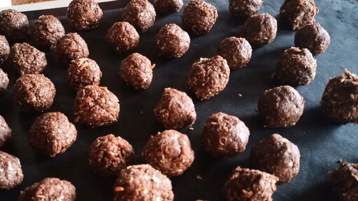 Chocolate coconut fudge balls on a tray, about half-way through the freezing process. They were finger-formed into balls about 3cm in diameter.